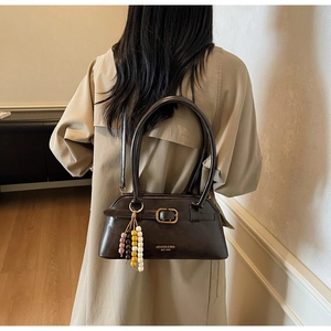 Detail of dark brown retro shoulder bag with metallic buckle and beaded pendant accessory