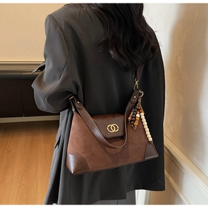 Detail of vintage brown tote bag with gold hardware and wooden bead tassel ornament