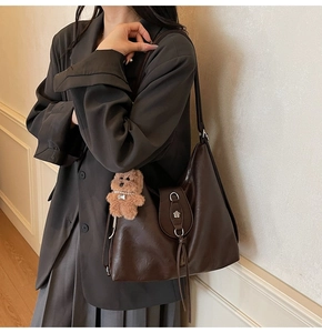 Detail view of dark brown PU leather tote bag with tassel and plush bear charm decoration