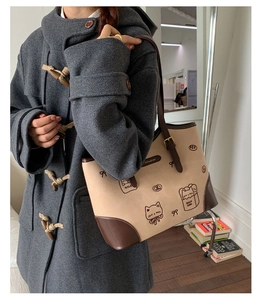 Dettaglio della borsa tote vintage con illustrazione di gatto su cappotto grigio