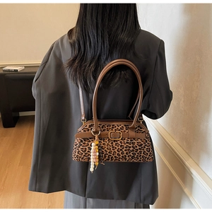 Detail of leopard print handbag with brown leather straps and vintage gold buckle