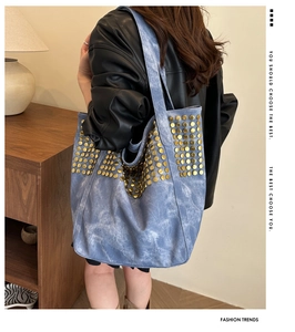Détail du sac cabas en denim bleu avec clous dorés décoratifs et design spacieux