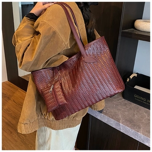 Détail d'un sac cabas tressé bordeaux montrant sa texture et sa pochette assortie