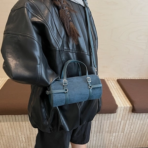 Minimalist navy blue cylinder bag with adjustable strap and vintage buckle detail