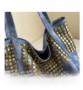 Détail d'un sac cabas en jean bleu avec rivets dorés polis et texture punk