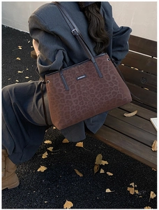 Close-up of leopard print tote bag with leather strap on an autumn park bench