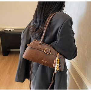 Detail of vintage brown leather bag with gold buckle and beaded charm accessory