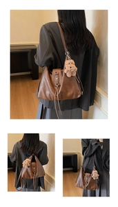 Close-up of brown soft leather tote with fringe detail and cute teddy bear charm