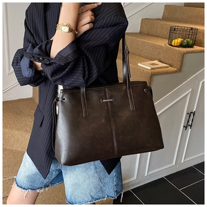 Detail of BROBOOM brown leather tote bag with metal logo and contrast stitching