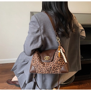 Detail view of large leopard print tote bag with gold ring buckle and vintage bead charm