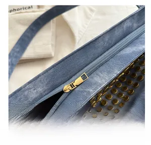 Détail de la fermeture éclair en métal et des rivets dorés sur le sac fourre-tout bleu