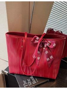Bolso tote rojo grande con textura ondulada vertical y accesorio de pañuelo decorativo