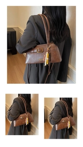 Detail of a brown vintage leather shoulder bag with a beaded tassel and golden buckle
