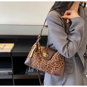Detail of leopard print tote bag with brown leather accents and gold buckle hardware