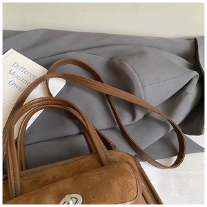 Detail of brown suede handbag featuring silver twist lock and neat stitching work