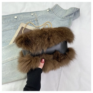 Detail of black pebbled leather bag with brown faux fur trim and gold chain strap