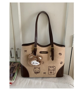 Dettaglio del ricamo a gatto e della targhetta del brand sulla borsa tote bicolore