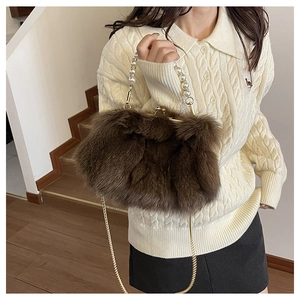 Detail of dark brown plush crossbody bag with pearl handle and golden chain strap