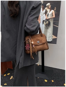 Close-up of vintage brown suede bowling bag with silver twist lock and bear charm