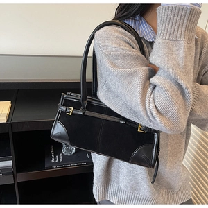 Detail of black baguette bag showing suede and smooth leather texture with gold buckle