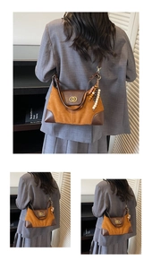 Detail of retro suede patchwork underarm bag with gold rings and wood bead charm