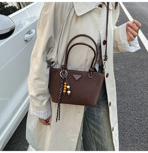 Detail of dark brown pleated hobo bag with triangle metal logo and wood bead tassel