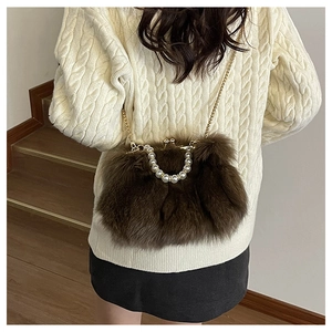 Detail of brown faux fur crossbody bag featuring pearl handle and gold chain strap