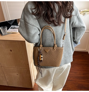 Detailed view of brown quilted PU leather bucket bag with wooden bead charm and metal tag