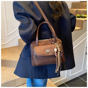 Brown suede bowling bag featuring silver turn-lock and woven tassel shown on a model