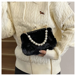 Close-up of black faux fur bag with pearl handle and golden chain on a white sweater
