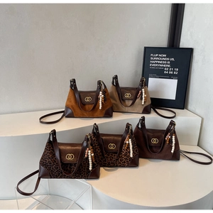 Detail of vintage suede shoulder bags featuring metal double-ring locks and beaded tassels
