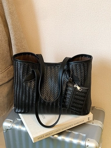 Grand sac cabas tressé noir avec pochette assortie sur une valise argentée
