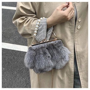 Detail of grey faux fur crossbody bag featuring luxury pearl handle and gold chain strap
