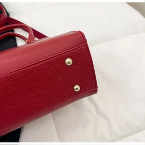 Detail of red lychee grain leather handbag bottom with protective gold metal feet studs