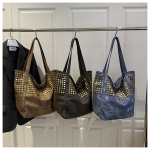 Détail de grands sacs cabas cloutés en marron, gris et bleu avec rivets dorés