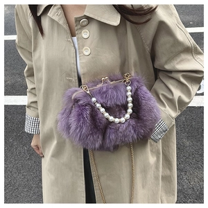 Purple faux fox fur bag with pearl handle and gold chain strap shown on khaki trench coat