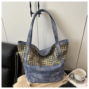 Détail d'un sac cabas en denim bleu foncé avec des rivets dorés denses et texture métal