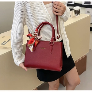 Deep red lychee grain leather handbag featuring gold branding and a silk scarf on the handle