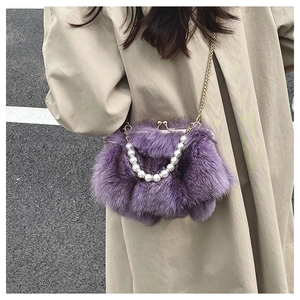 Macro shot of purple plush crossbody bag with pearl strap and golden chain details