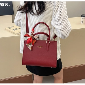 Detail of red bridal leather handbag with luxury lychee texture and decorative silk scarf