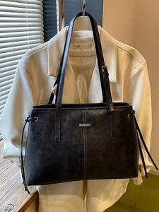 Classic black faux leather tote bag with white stitching and stylish tassel details
