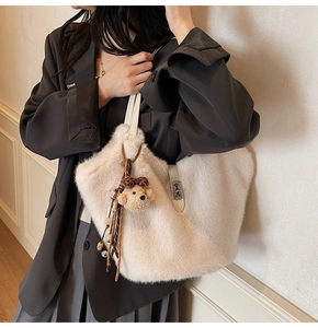 Détail du sac cabas en fausse fourrure blanc cassé avec boucle en H et breloque ours