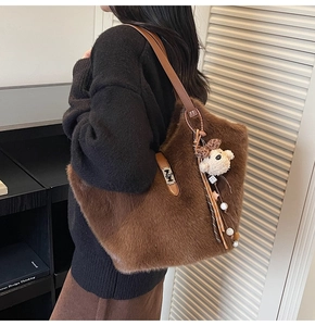 Détail du sac cabas en peluche montrant la texture brune, la sangle en cuir et le charm ours