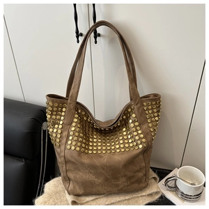 Détail d'un sac cabas marron avec des clous dorés et une texture mate vintage