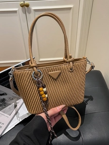 Caramel pleated bucket bag with triangle logo and wooden bead charm held by hand