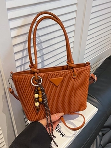 Brown quilted bucket bag with top handles and a crossbody strap in a lifestyle setting