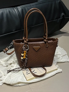 Brown pleated bucket bag with vertical texture and bohemian bead tassel accessory