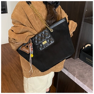 Detail of black tote bag with quilted front pocket, gold hardware, and metal chain strap