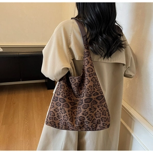 Détail d'un grand sac cabas à imprimé léopard porté par un mannequin en trench-coat