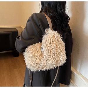 Close-up of cream faux shearling bucket bag with plush texture and brown leather strap